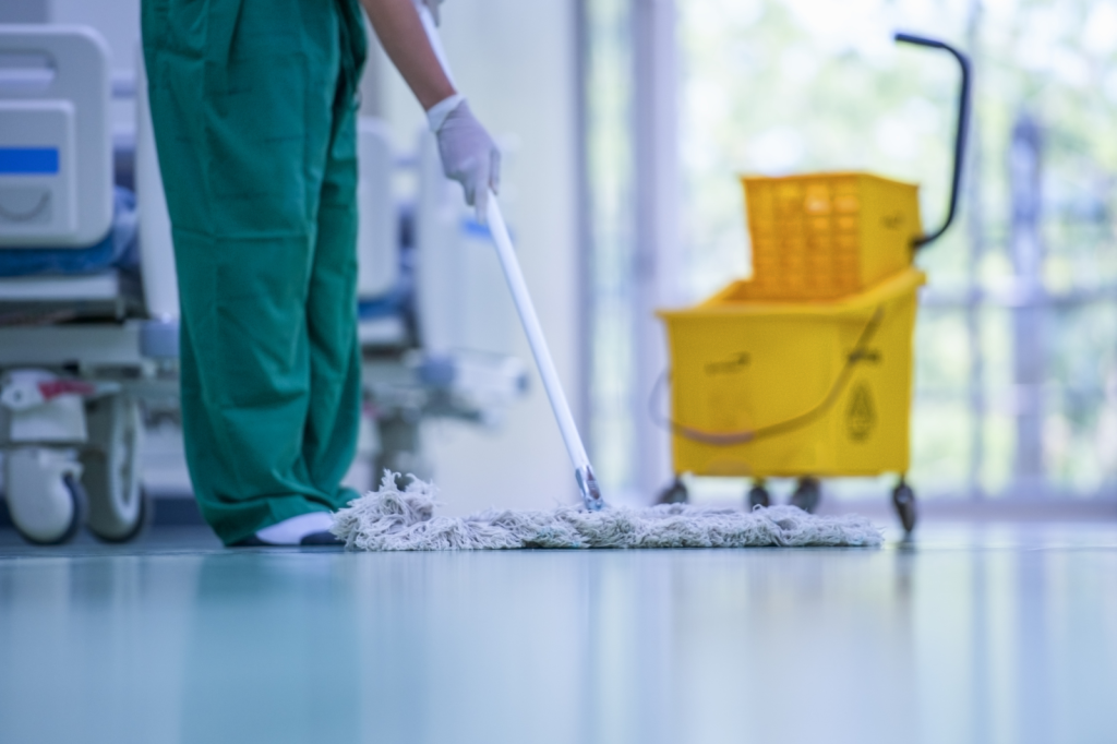 Professionele schoonmaak van een vloer in een medische instelling met een mop en schoonmaakkar.